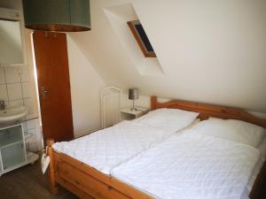 a bedroom with a white bed and a sink at Ferienwohnungen und Ferienhaus im Nixenweg in Hohwacht