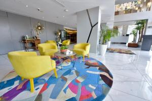 a lobby with yellow chairs and a colorful rug at Bram Hotel in Jeddah
