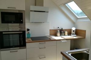 a kitchen with white cabinets and a sink and a window at Appartement chaleureux, montagne et cures in Argelès-Gazost