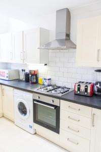 cocina con fogones, lavadora y fregadero en Mansion House with Spacious Apartments close to Excel London and CanaryWharf, en Londres