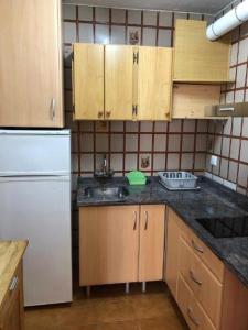 una cucina con armadi in legno e frigorifero bianco di Isla Blanca II 3 ET 249 PL a Es Pujols