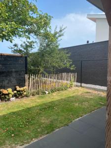 a wooden fence in a yard with a grass field at Studio appartement 1nul9 in Renesse