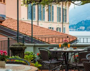 a patio with tables and chairs and a view of the water at Hotel Bellagio in Bellagio