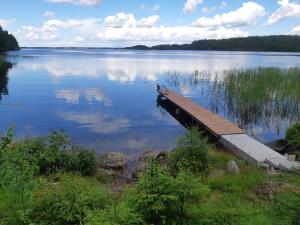 a wooden dock on a large lake with clouds in the sky at Saimaa Raikala in Vuoriniemi