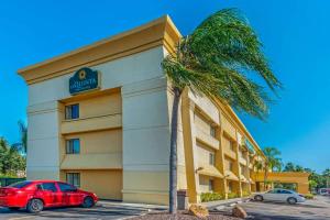 a red car parked in front of a hotel with a palm tree at La Quinta by Wyndham Tampa Brandon West in Tampa