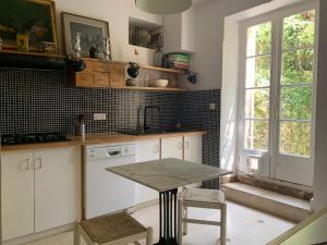 a kitchen with white cabinets and a table and a window at La Maison Carrée - Villa de charme - Clim & Piscine chauffée in Les Eyzies-de-Tayac