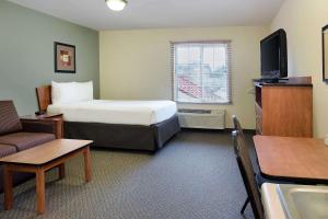 a small hotel room with a bed and a tv at WoodSpring Suites Raleigh Northeast Wake Forest in Raleigh