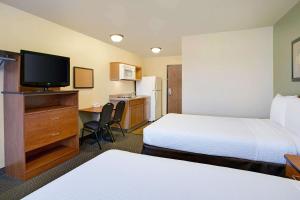 a hotel room with two beds and a desk with a television at WoodSpring Suites Raleigh Northeast Wake Forest in Raleigh