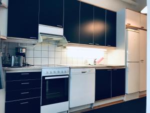 una cucina con armadietti neri ed elettrodomestici bianchi di Kamppi City Apartment a Helsinki