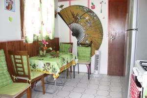 una sala da pranzo con tavolo, sedie e ventilatore di Locat dépôt a Bouillante
