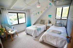 a bedroom with two beds and a chair and windows at Cedar Country Retreat in Halls Gap