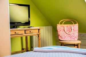 a bedroom with a bed and a television and a chair at L'Hippocampe in Plouharnel