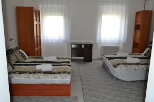 a room with two beds and a table and two windows at Fészek Apartmanház in Tapolca