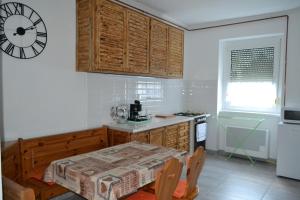 a kitchen with a table and a clock on the wall at Fészek Apartmanház in Tapolca