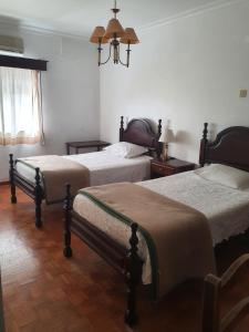 a bedroom with two beds and a chandelier at Hotel Novo Dia in Meda