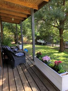 a wooden deck with a chair and flowers on it at Cedar Country Retreat in Halls Gap