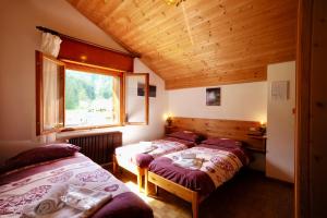 a bedroom with three beds and a window at Rifugio Palafavera in Val di Zoldo
