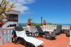 eine Terrasse mit Stühlen, einem weißen Zaun und dem Meer in der Unterkunft Casa Los Palitos in Monte de Breña