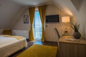 een slaapkamer met een bed, een bureau en een televisie bij Vitis Kúria 7171 Balatonrendes in Balatonrendes