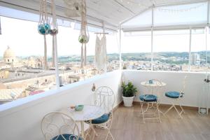 een balkon met tafels en stoelen en uitzicht op de stad bij Noto da Quassu' Bed and Breakfast in Noto