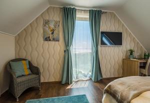 a bedroom with a bed and a chair and a window at Vitis Kúria 7171 Balatonrendes in Balatonrendes