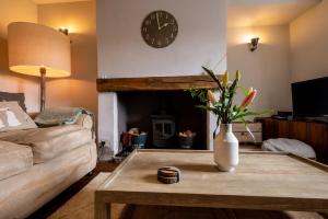 a living room with a coffee table and a clock at Sett Cottage in Hayfield