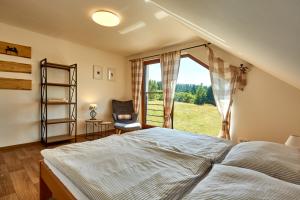 a bedroom with a bed and a chair and a window at Chalupa pod Plešivcem in Abertamy