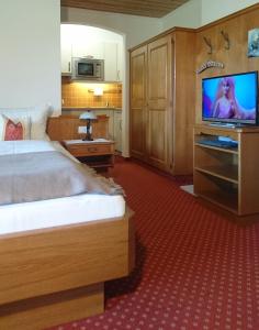 um quarto de hotel com uma cama e uma televisão de ecrã plano em Gästehaus Auer em Holzgau