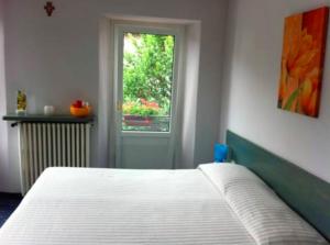 ein Schlafzimmer mit einem weißen Bett und einem Fenster in der Unterkunft Albergo Centrale in Fino del Monte
