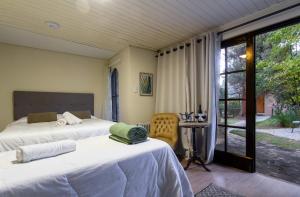 1 dormitorio con 2 camas, mesa y ventana en Pousada Casa Mantiqueira proxima ao capivari en Campos do Jordão