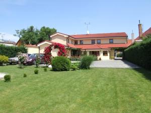 una casa con un patio con césped verde y flores en Penzion 77 - Garni en Pezinok