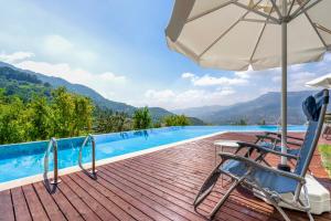 a wooden deck with chairs and an umbrella next to a swimming pool at Avena Mountain Boutique Hotel - Adults Only in Antalya