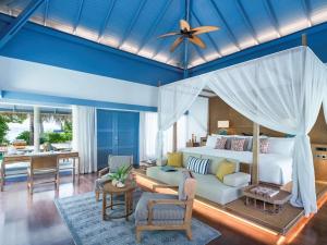 a bedroom with a bed and a living room at Raffles Maldives Meradhoo in Gaafu Alifu Atoll