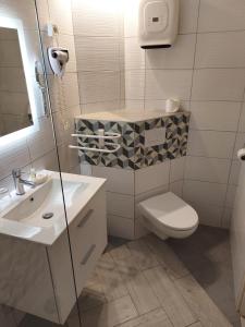 La salle de bains est pourvue de toilettes, d'un lavabo et d'un miroir. dans l'établissement The Originals City, Hôtel Azur, Fos-sur-Mer, à Fos-sur-Mer