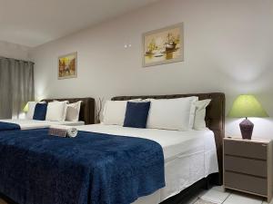 a bedroom with two beds with blue and white sheets at B & A Suites Inn Hotel - Quarto Luxo Safira in Anápolis