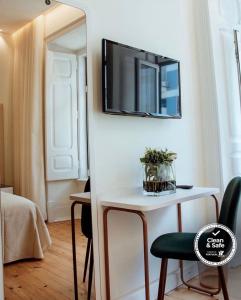 a room with a table with a mirror and a tv on the wall at Le Premier Lisbon Suites in Lisbon