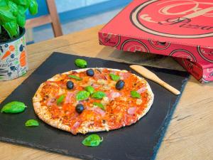 uma pizza sentada numa mesa ao lado de uma caixa em ibis budget Nice Californie Lenval em Nice