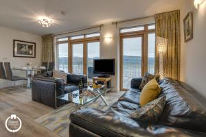 a living room with a leather couch and a television at The Old Stables Aberdyfi apartment 3 in Aberdyfi