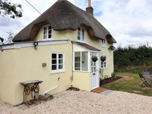 a thatched cottage with a thatched roof at Primrose Cottage in Moreton