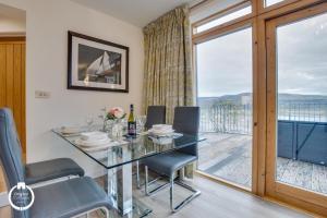 a dining room with a glass table and chairs and a balcony at The Old Stables Aberdyfi apartment 3 in Aberdyfi