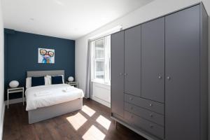 una camera con letto e parete blu di homely - Central London Liverpool Street Apartments a Londra