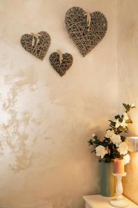 eine Wand mit Herzen an der Wand und eine Vase mit Blumen in der Unterkunft Ca’ Anna in Biennale in Venedig