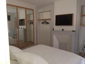 een slaapkamer met een bed en een televisie aan de muur bij L'évasion in Honfleur