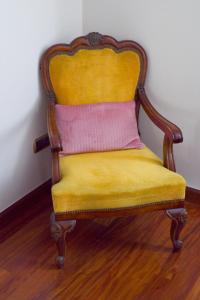 a yellow chair with a pink pillow on a wooden floor at Plaza Mayor Centro - Familiar-Sin Ruido-Wifi-Ascensor in Valladolid