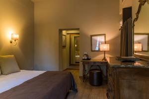 a bedroom with a bed and a desk and a mirror at Hotel Royal Victoria, by R Collection Hotels in Varenna