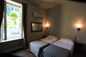 two beds in a hotel room with a window at Hotel Royal Victoria, by R Collection Hotels in Varenna