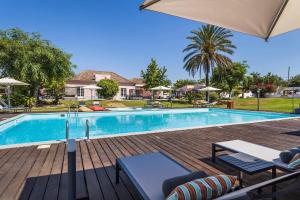 a swimming pool with chairs and an umbrella at Quinta de Santa Margarida - Charm Country House in Tavira