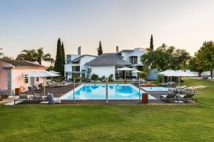 a pool with chairs and umbrellas in a yard at Quinta de Santa Margarida - Charm Country House in Tavira