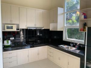 a kitchen with white cabinets and black counter tops at Villa Sanlias in Bogor