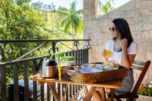 Eine Frau, die an einem Tisch mit einem Obstkorb sitzt. in der Unterkunft Villa Ayê Socorro SP - Pousada Petfriendly in Socorro